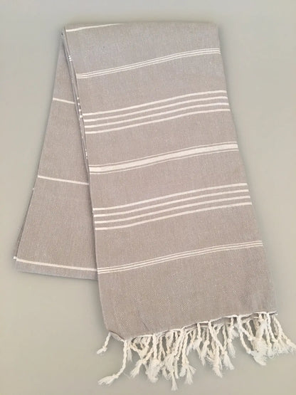 Light gray Turkish towel with white stripes and fringed edges, folded on a neutral background.