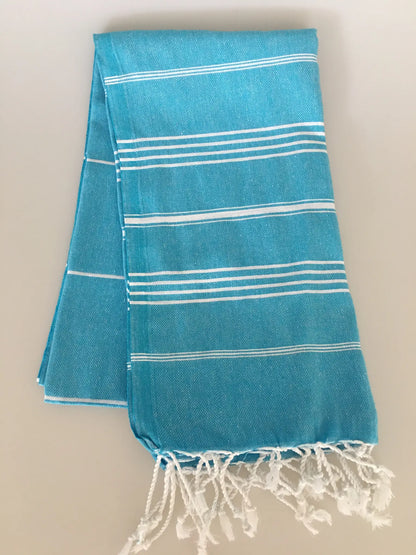 Aphrodisias Sultan Turkish towel in turquoise with white stripes, featuring fringed edges, folded flat on a neutral backgroun