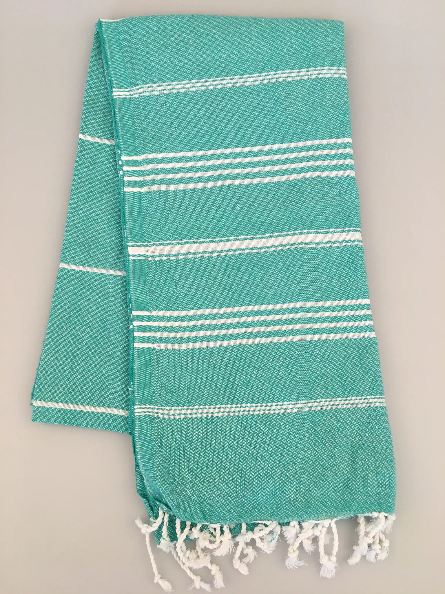 Aphrodisias Sultan Turkish towel in turquoise with white stripes and fringed edges, displayed flat on a light background.