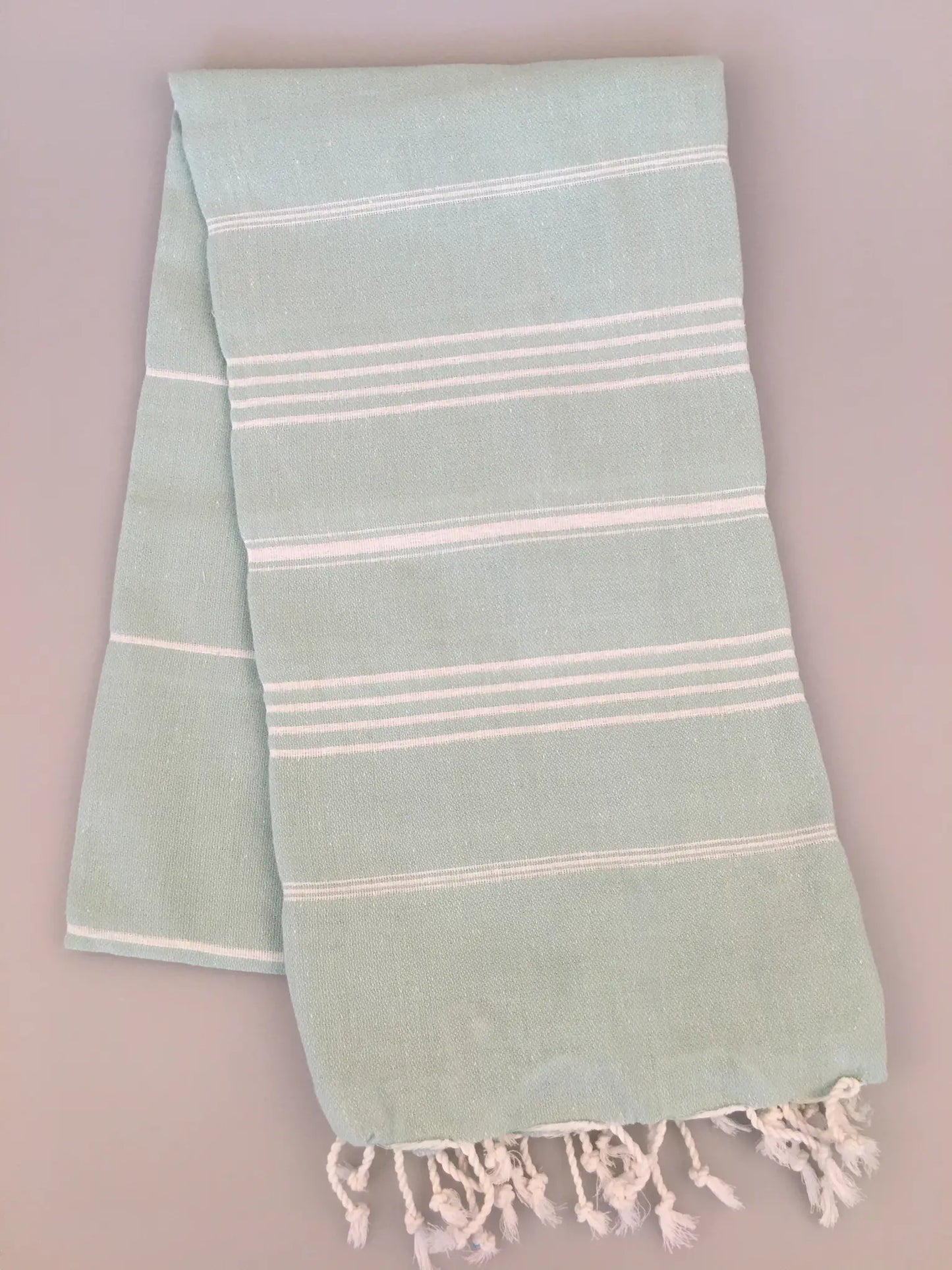 Aphrodisias Sultan Turkish Towel in light green with white stripes and fringed edges, laid flat on a neutral background.
