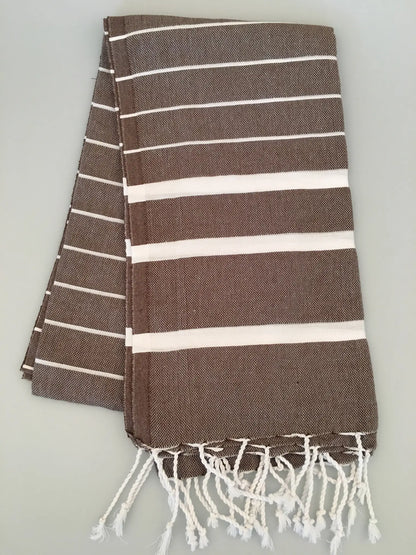 Brown and white striped Teos Turkish towel peshtemal with fringed ends, folded on a light background.