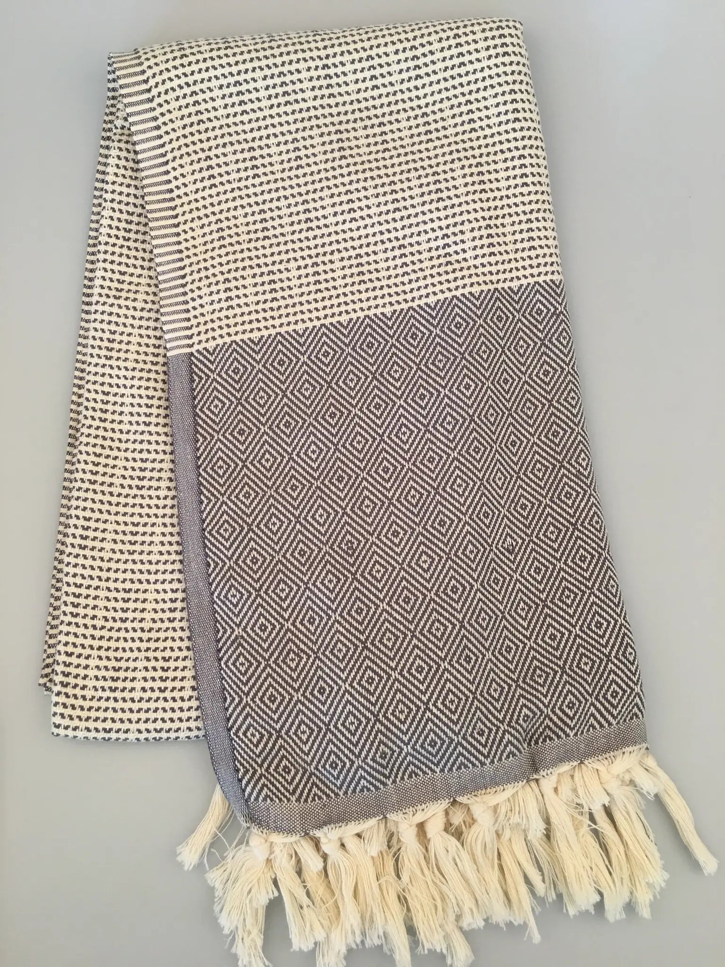 "Lycia Patara Turkish towel in beige and gray with diamond pattern, featuring fringed edges, laid flat on a light surface."
