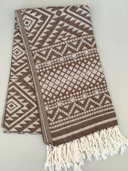 "Jacquard peshtemal in brown and cream with geometric patterns, featuring white fringes at one end."
