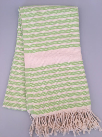 Green and white striped Hittite Turkish towel with fringed edges, folded on a light gray background.