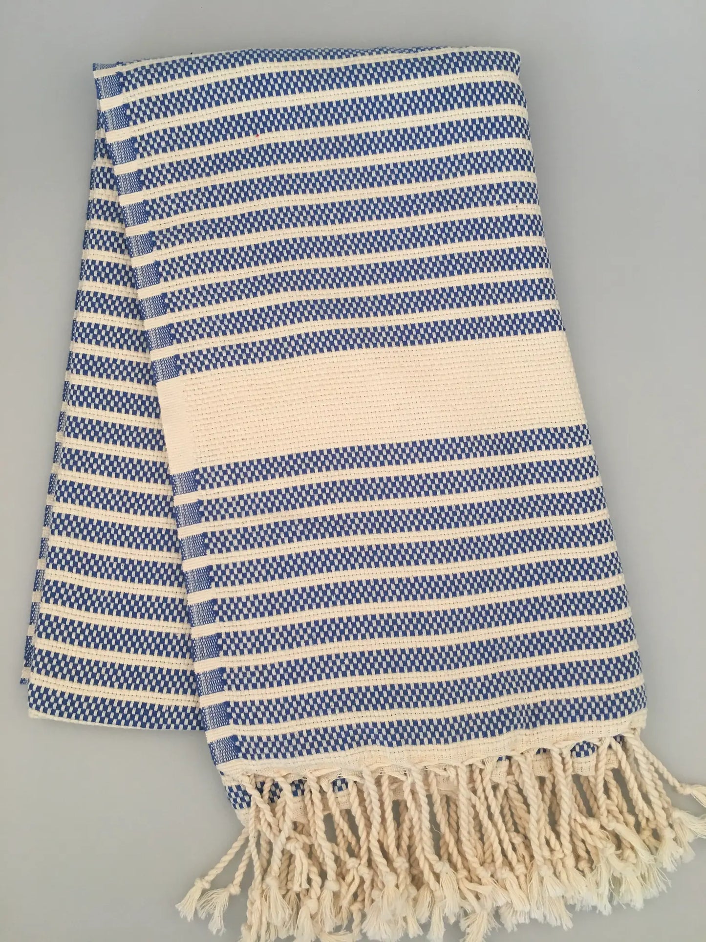 Blue and white striped Hittite Turkish towel with a woven texture and fringed edges, laid flat on a light background.