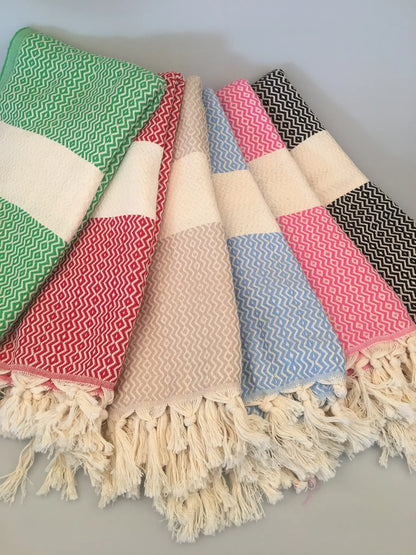 "Lycia Letoon Turkish towel in green, red, pink, blue, and black patterns, with fringed edges, laid flat on a light backgroun