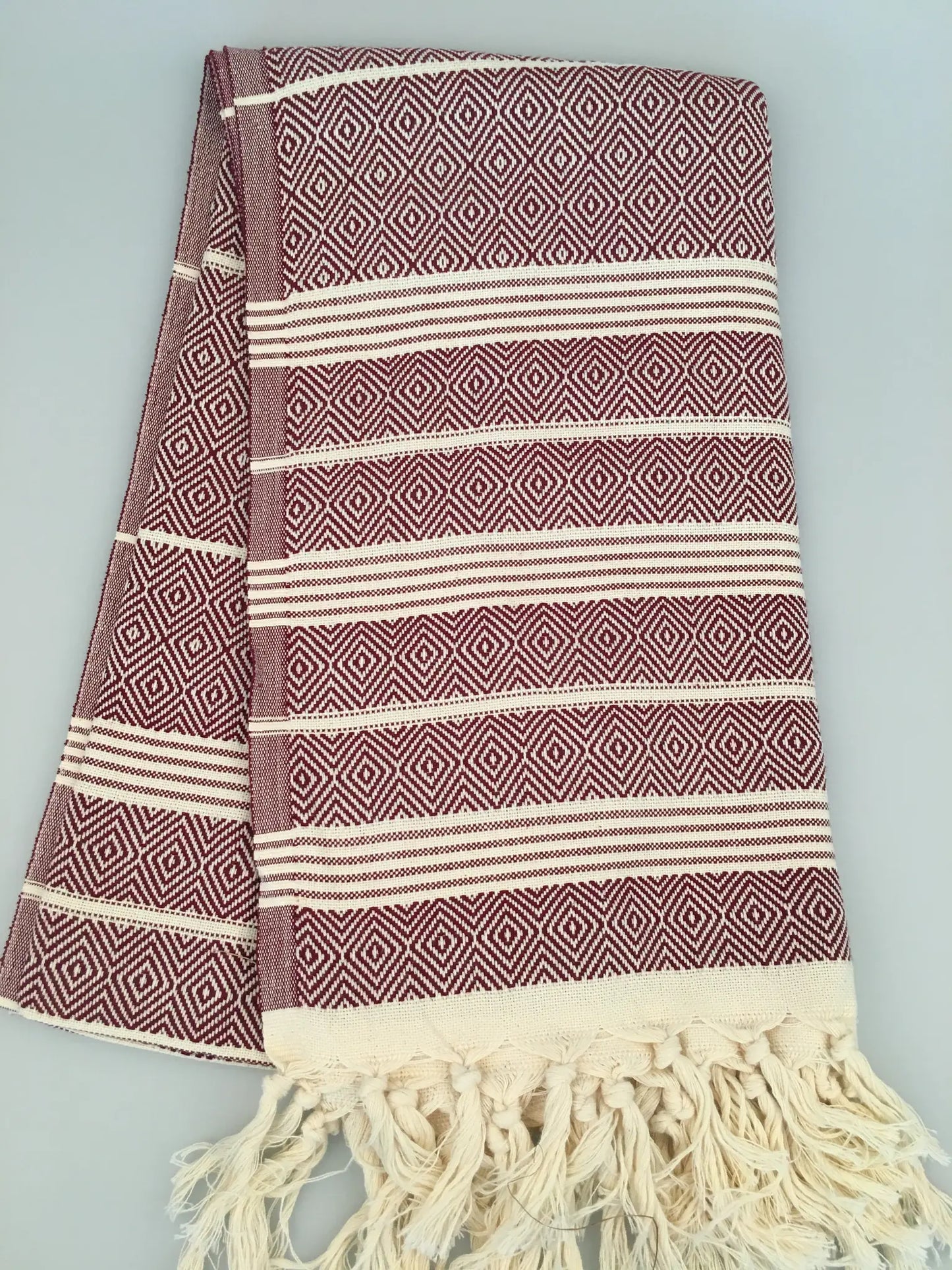 "Lycia Xanthos Turkish towel peshtemal in burgundy and cream with diamond patterns and fringed edges, folded view"
