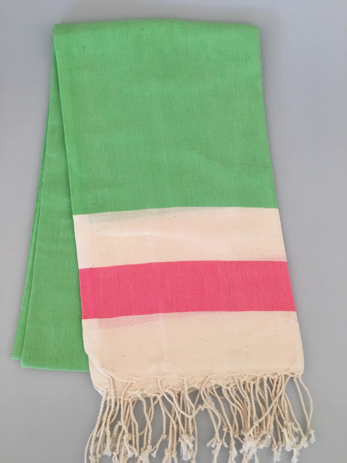 "Green peshtemal towel with a cream and pink striped section at the bottom, featuring fringed edges."