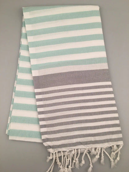 "Striped Tlos Turkish towel peshtemal in mint green and gray, featuring fringed edges, flat on a light background."