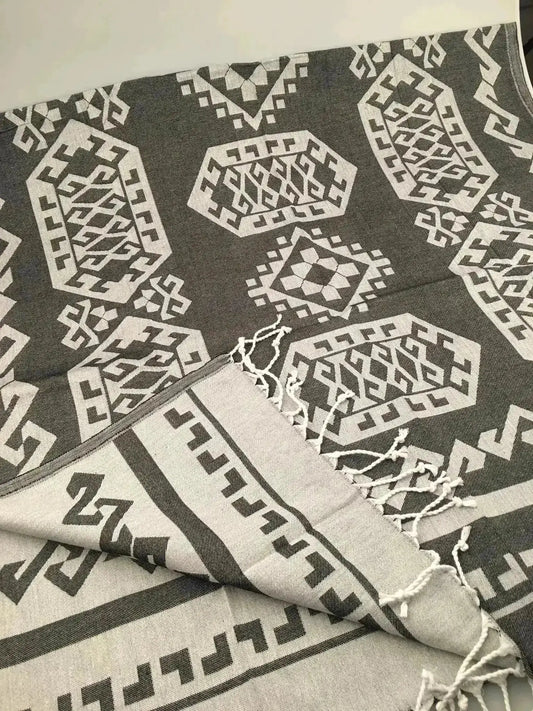 Gray and white Jacquard peshtemal with geometric patterns and fringed edges, folded on a light surface.