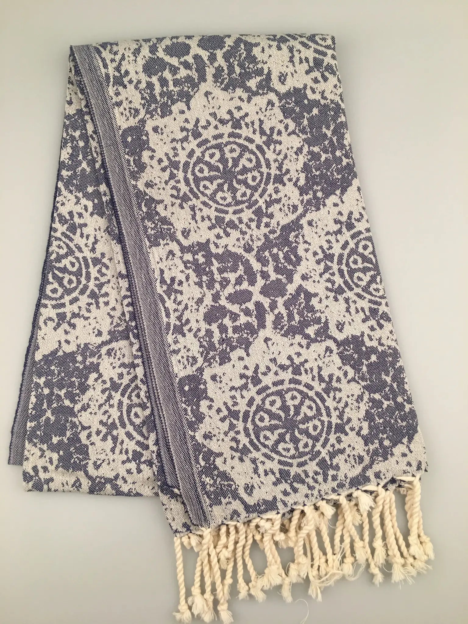 "Jacquard peshtemal towel in navy and cream with intricate floral pattern and fringed edges, folded view."