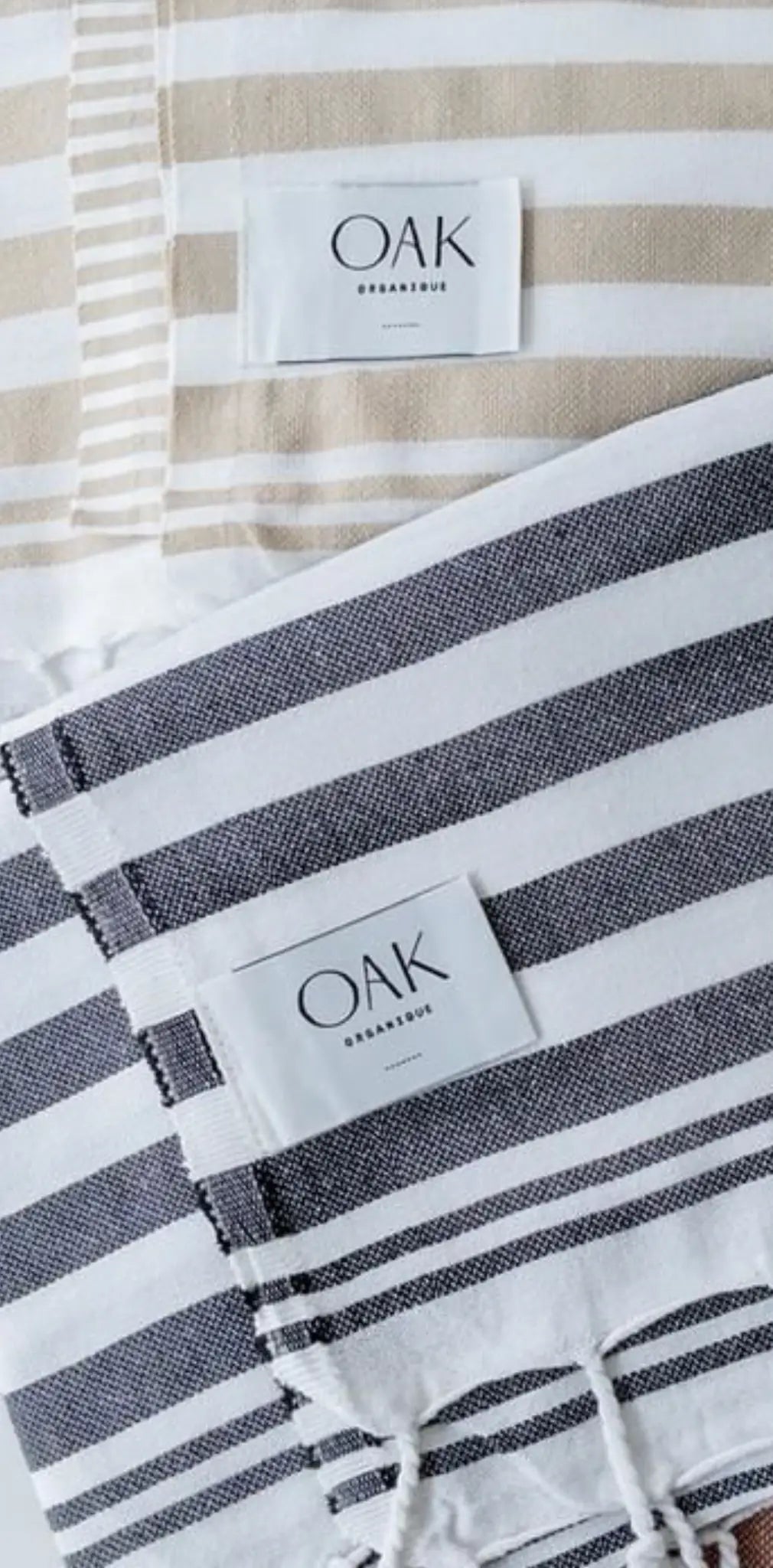 "Two cotton labels with horizontal stripes, one beige and one dark gray, each featuring a white tag with 'OAK' printed."