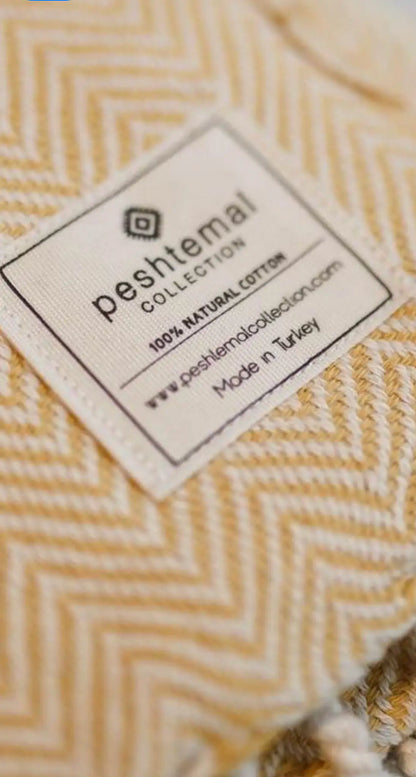 Woven cotton label with a herringbone pattern, featuring a white background and black text, corner view.