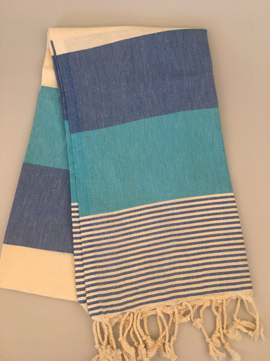 "Blue and turquoise striped Turkish towel with fringed edges, laid flat on a light background"