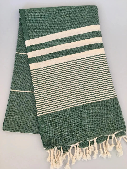 Green Turkish towel peshtemal with white stripes and fringed edges, folded neatly on a light background.