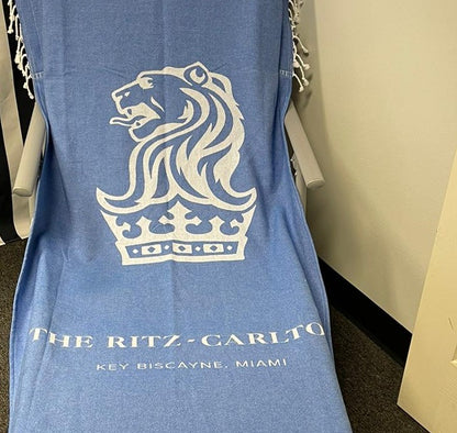 Jacquard-woven Turkish towel with Ritz-Carlton lion crest logo, convertible towel-to-tote design, detail crop
