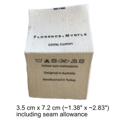 "Square cotton label with care instructions, beige background, black text, dimensions 3.5 x 7.2 cm."